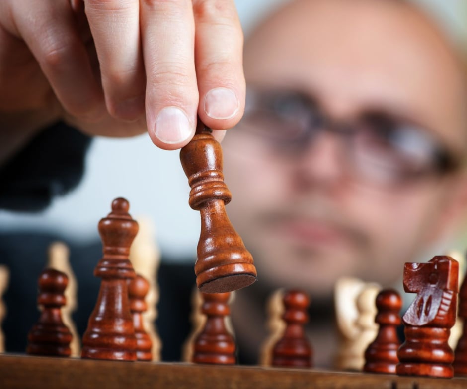 Person picking up a chess piece