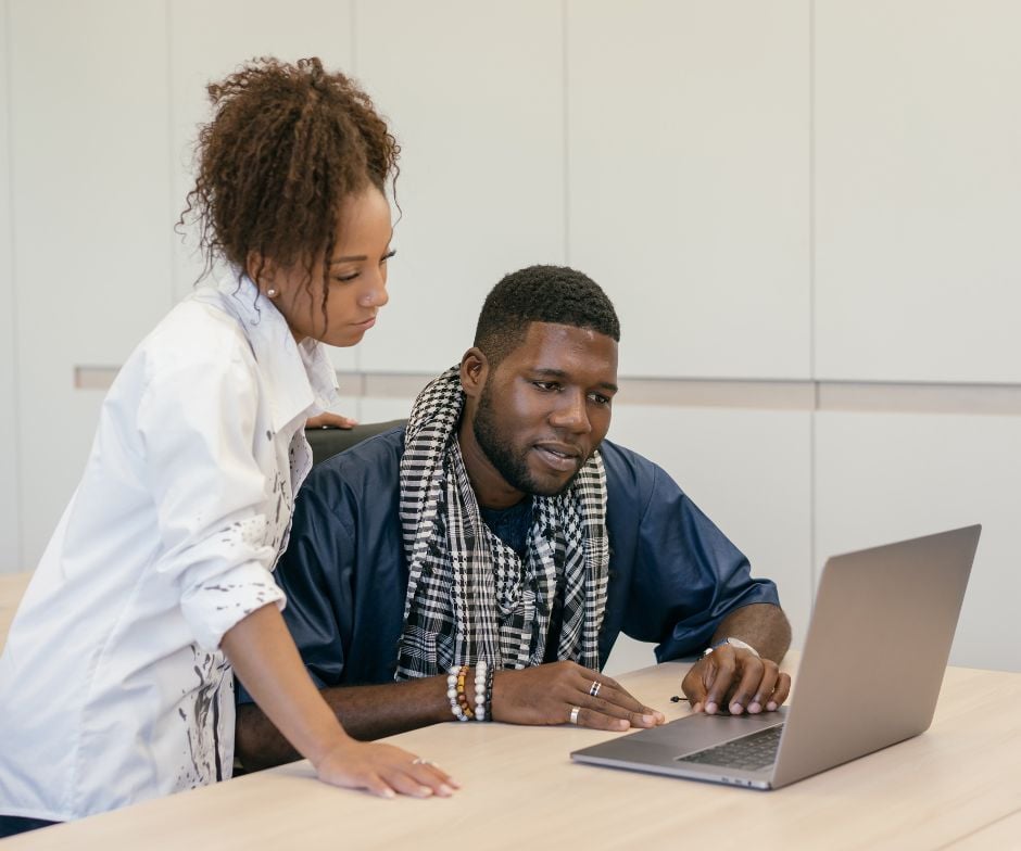 woman helping a man with a laptop