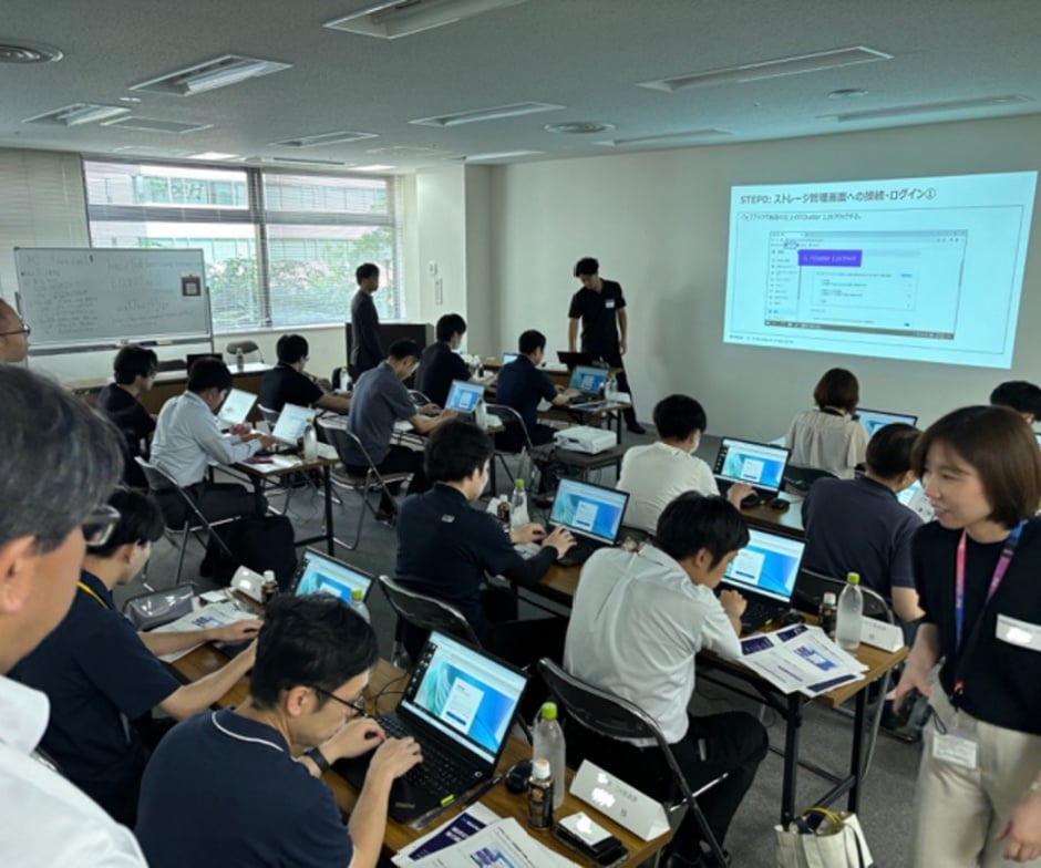 Participants attend a ransomware workshop, working on laptops while following a presentation in a classroom setting.