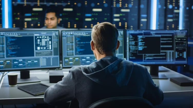 Persons sitting and working in front of monitors