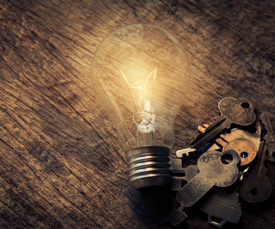 Lightbulb next to keys on a wooden table