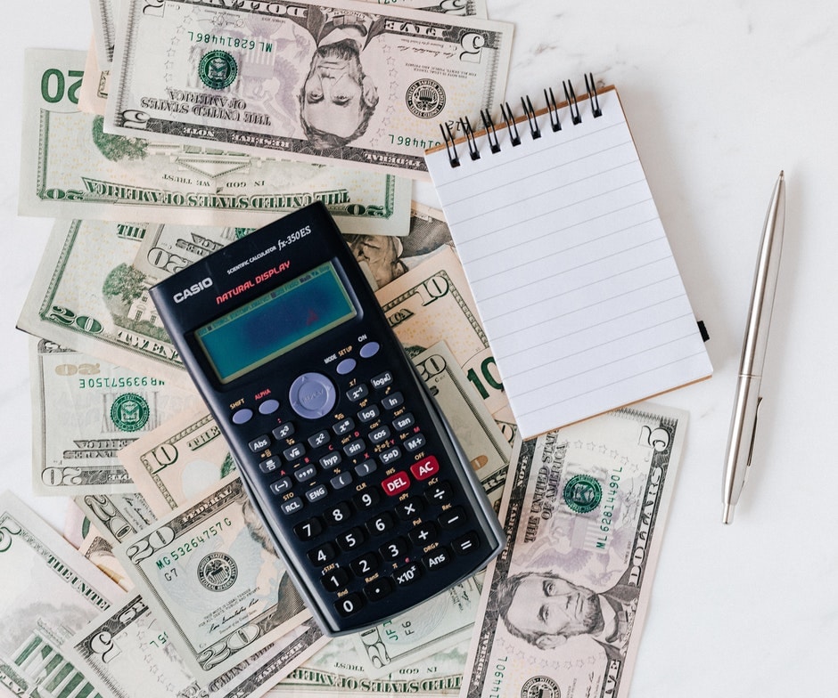 calculator and pad of paper on top of money