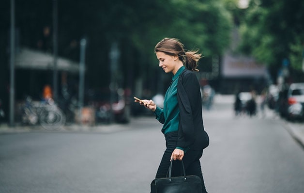 femme regardant son téléphone en traversant la rue