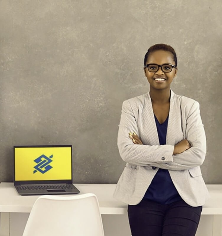 A woman standing by a desk that features a laptop
