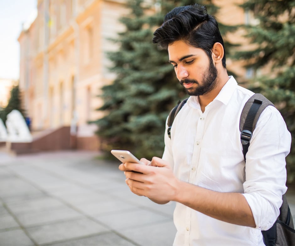 uomo che indossa uno zaino e guarda il telefono