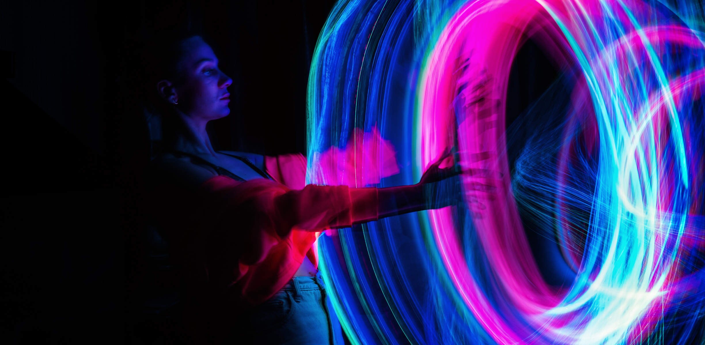 femme tendant la main dans un anneau de lumière multicolore et lumineux
