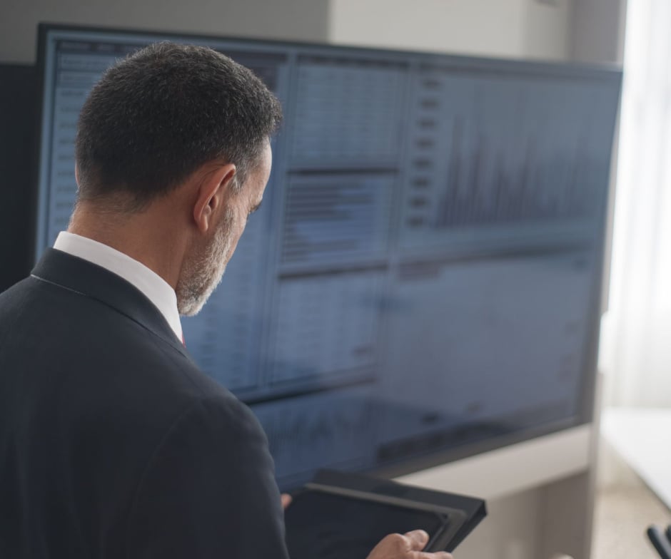 Business professional reviewing AI-driven data analytics dashboards on multiple monitors, showcasing enterprise data management and digital transformation.