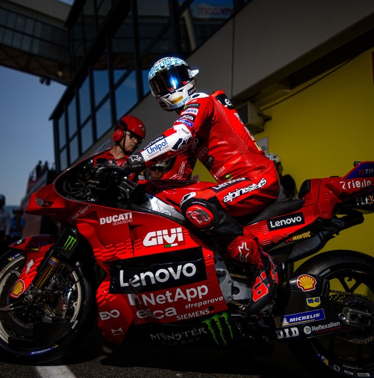 A Ducati rider seated on a motorcycle, trackside at a MotoGP event in Italy