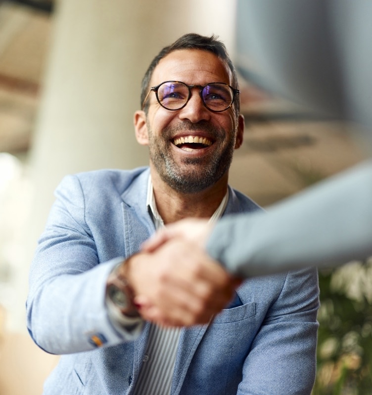 Person smiling and shaking someone's hand