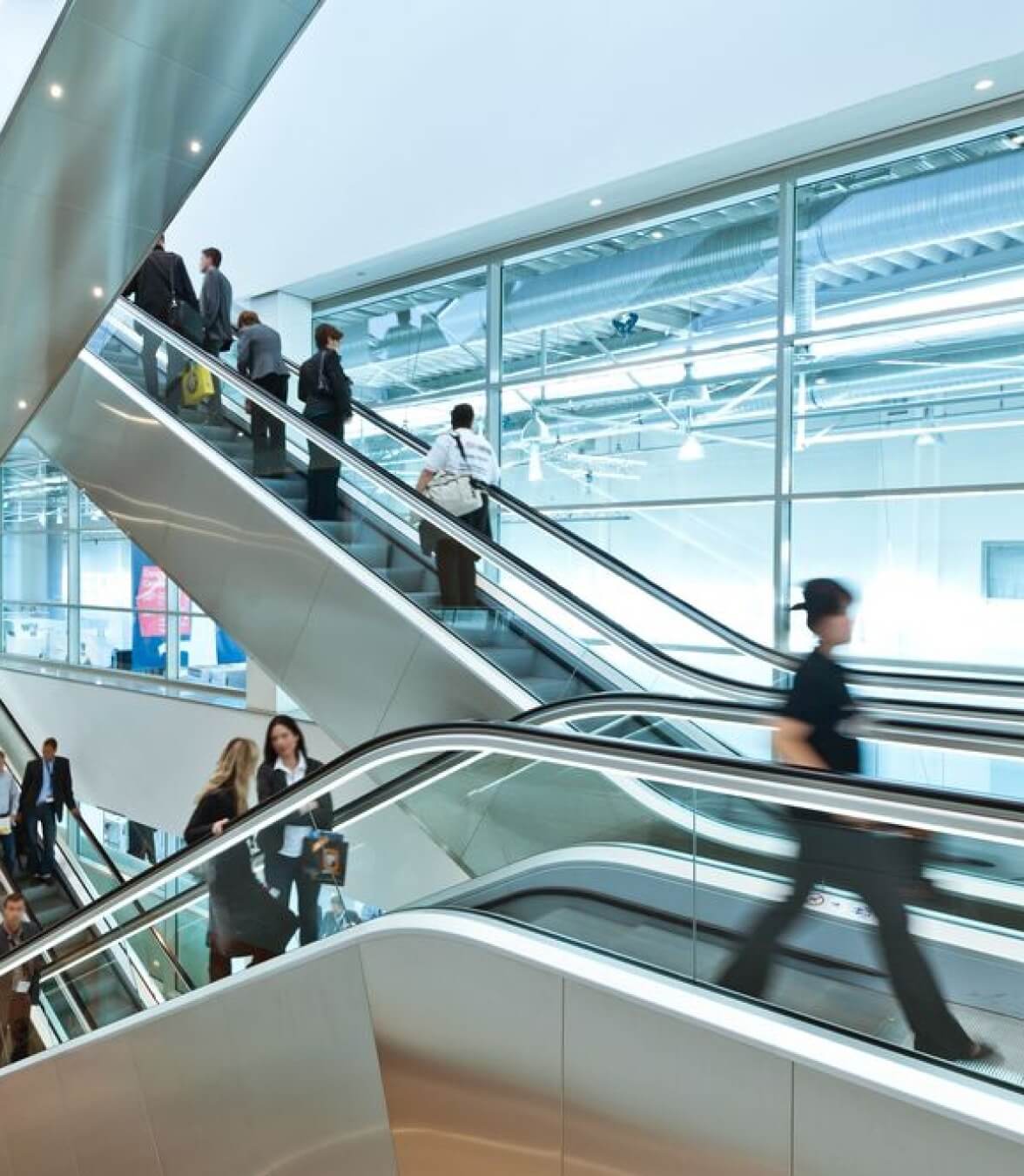 people walking and taking escaltor inside the building