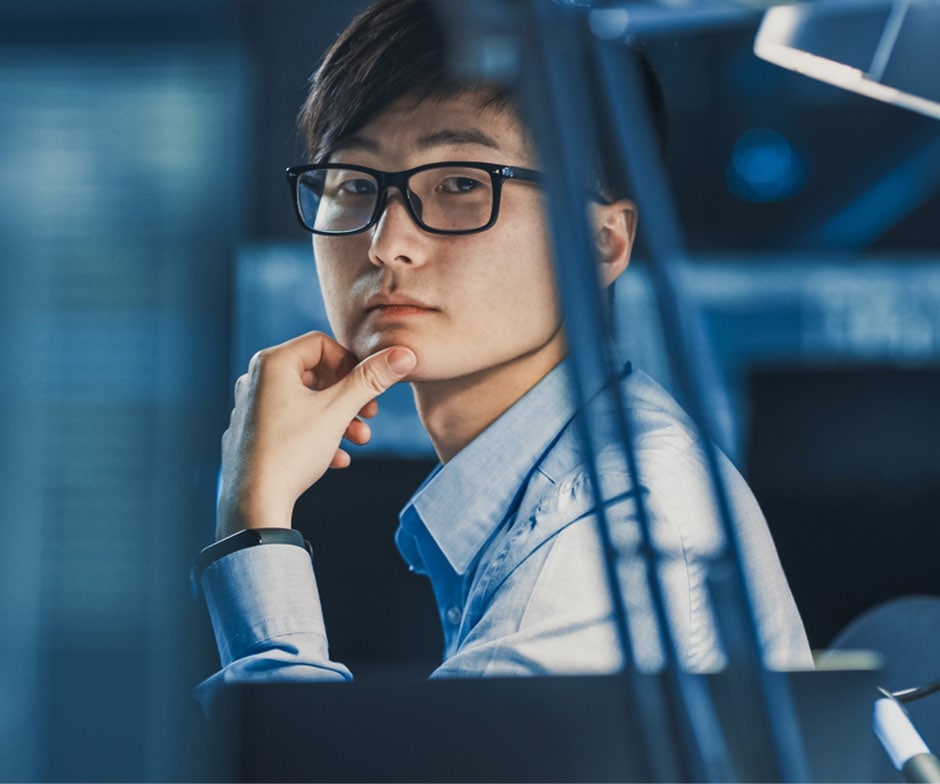 homme à lunettes regardant pensivement depuis son bureau