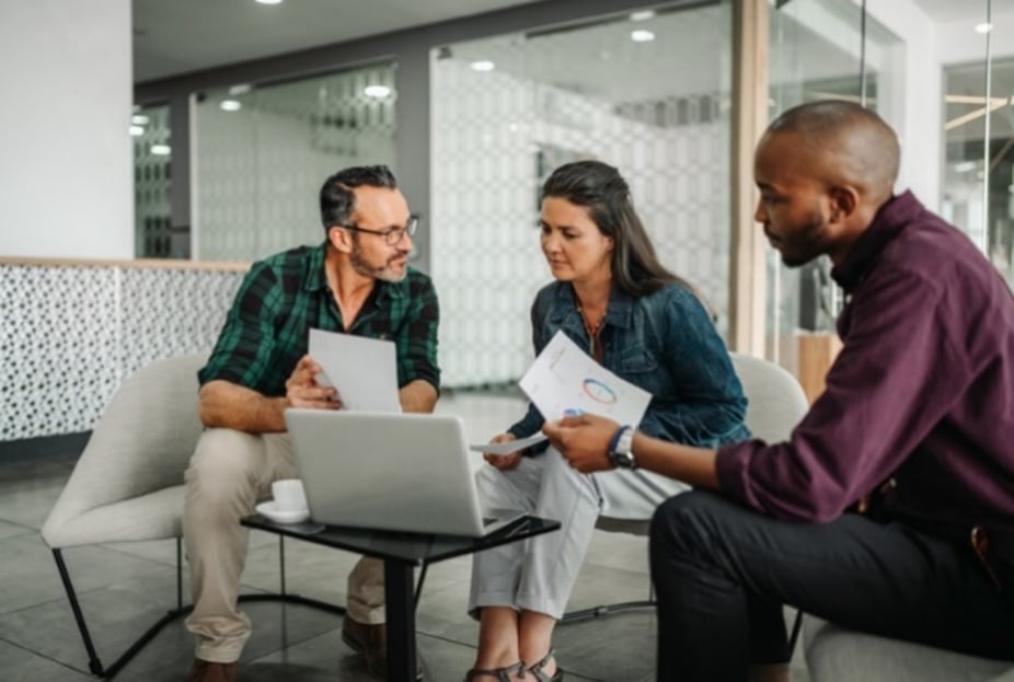 people sitting in front of coffee table looking at data and discussing