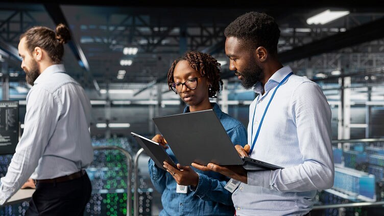 Équipe collaborant avec des ordinateurs portables et des tablettes dans un environnement de data center.