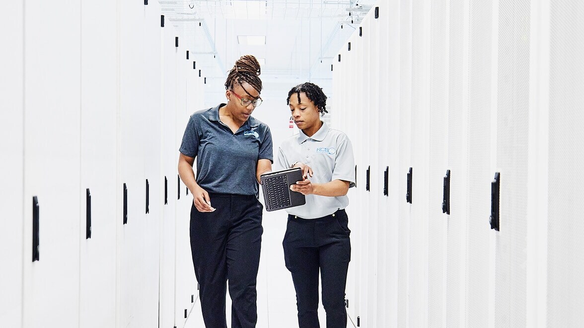 Two persons discussing by looking into the tab and walking