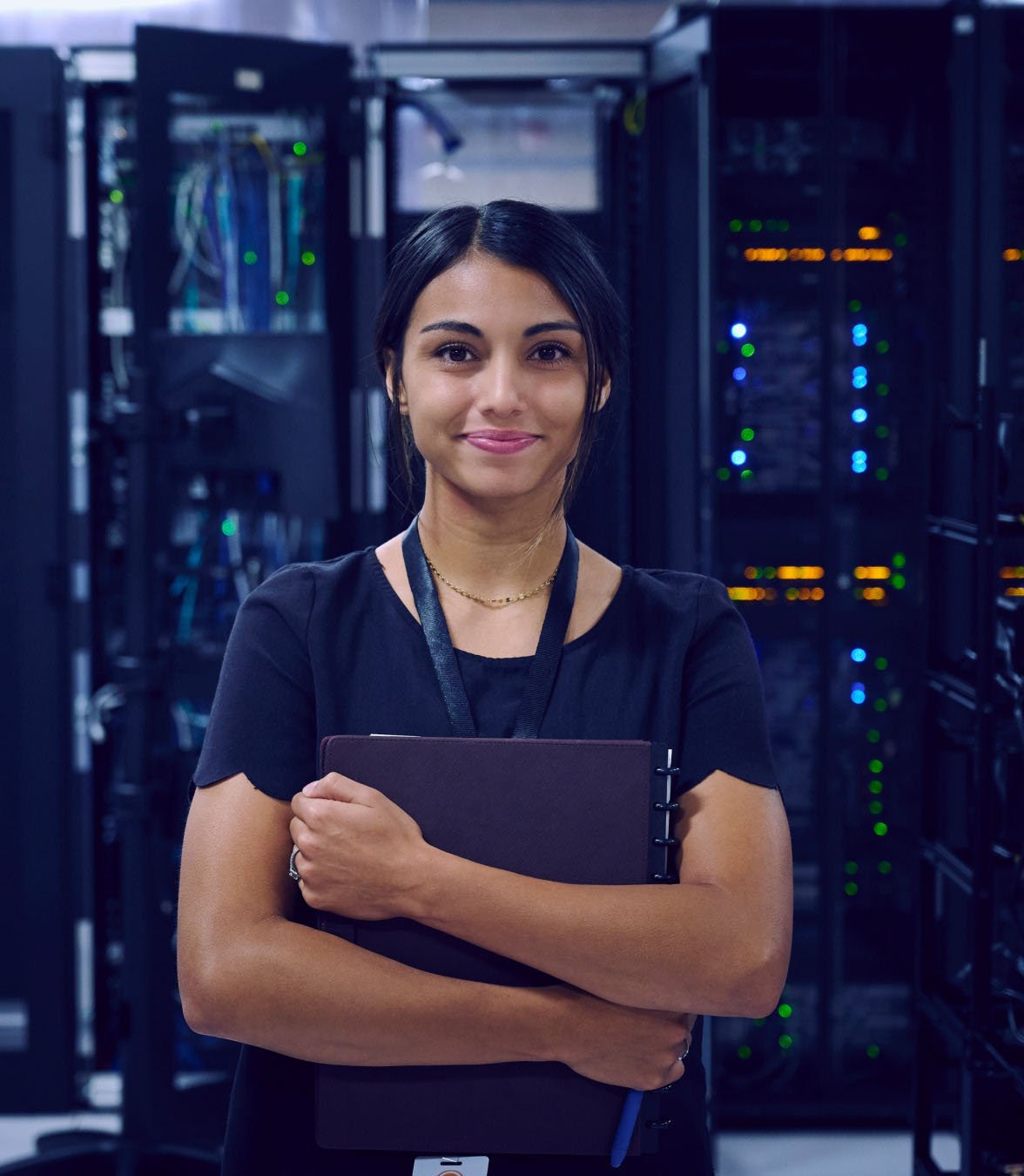 A person standing in a data center aisle while working on equipment in front of tall server racks.