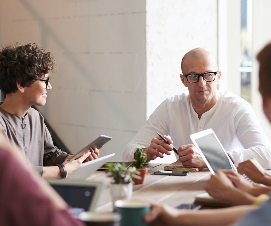 group of people sitting on a table holding electronic gadgets