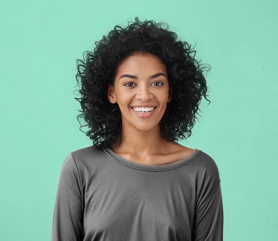 smiling woman in gray shirt in front of green background