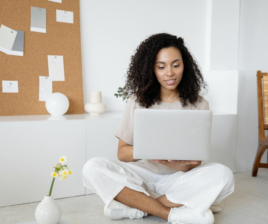 A Person sitting holding a laptop and working