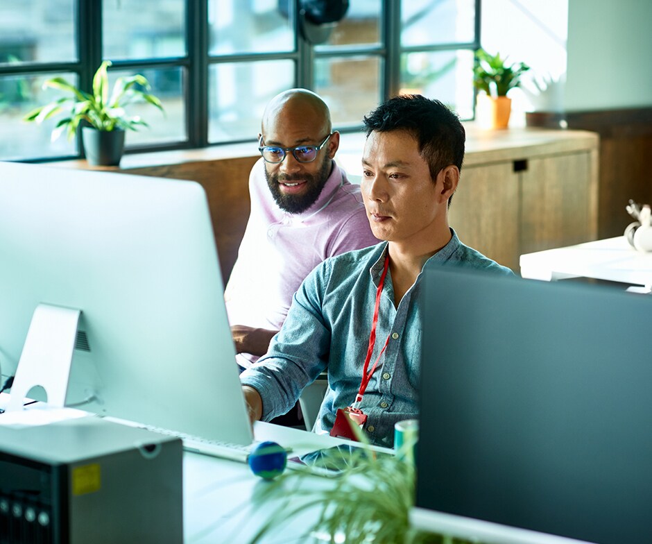 two people working in an office with laptops