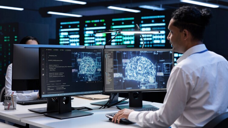 uomo che lavora a una scrivania con due schermi monitor