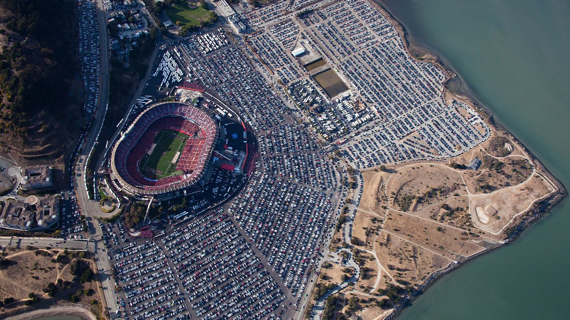 Vue aérienne d'un stade bondé des San Francisco 49ers entouré de parkings pleins à côté de l'eau.