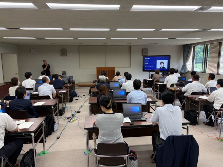 プレゼンターが会議室でノートパソコンを使用する参加者向けに実践的なサイバーセキュリティ研修セッションを実施している。